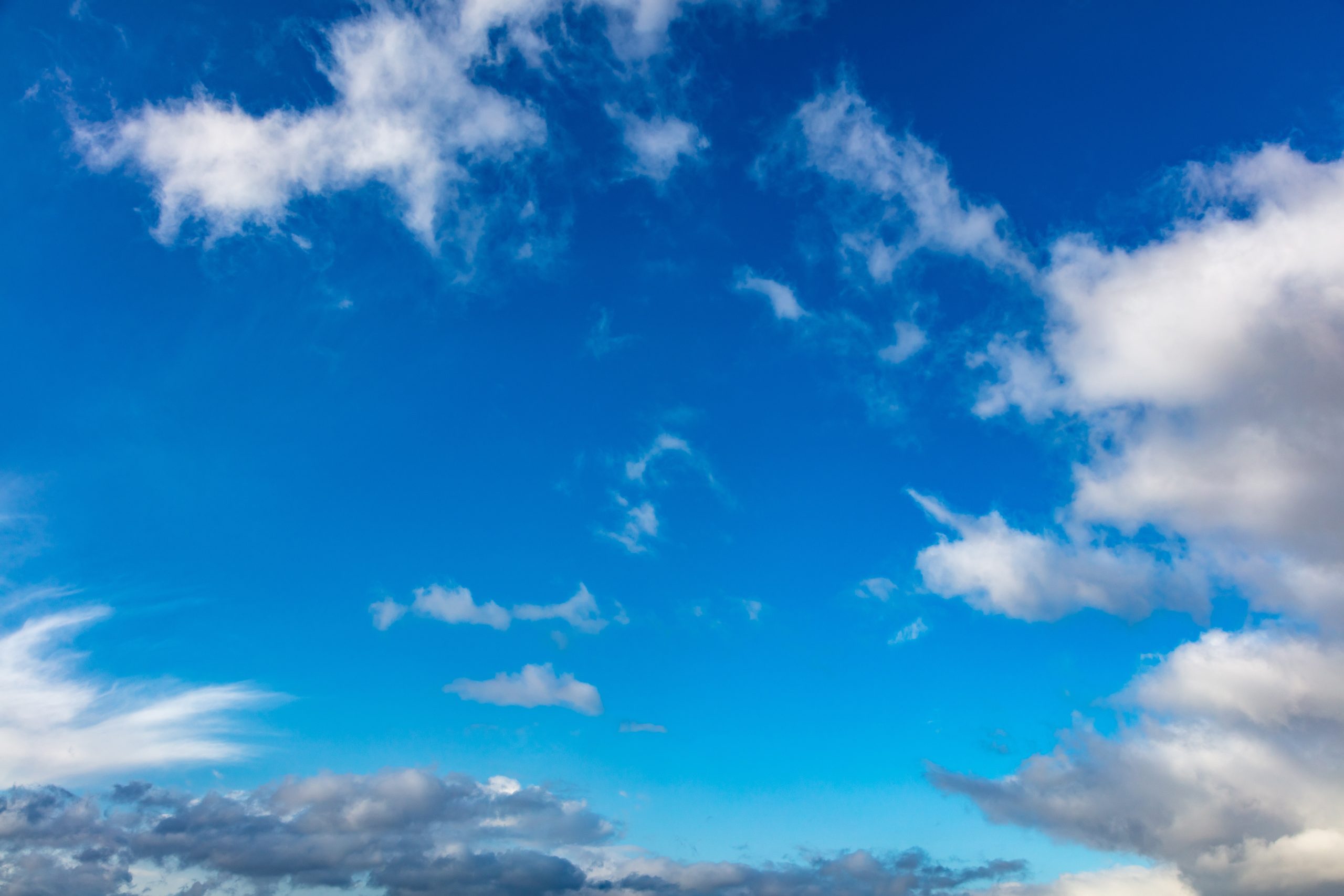 A bright blue sky with scattered white clouds and some darker clouds near the horizon, creating a peaceful and open atmosphere that inspires wellness and tranquility.